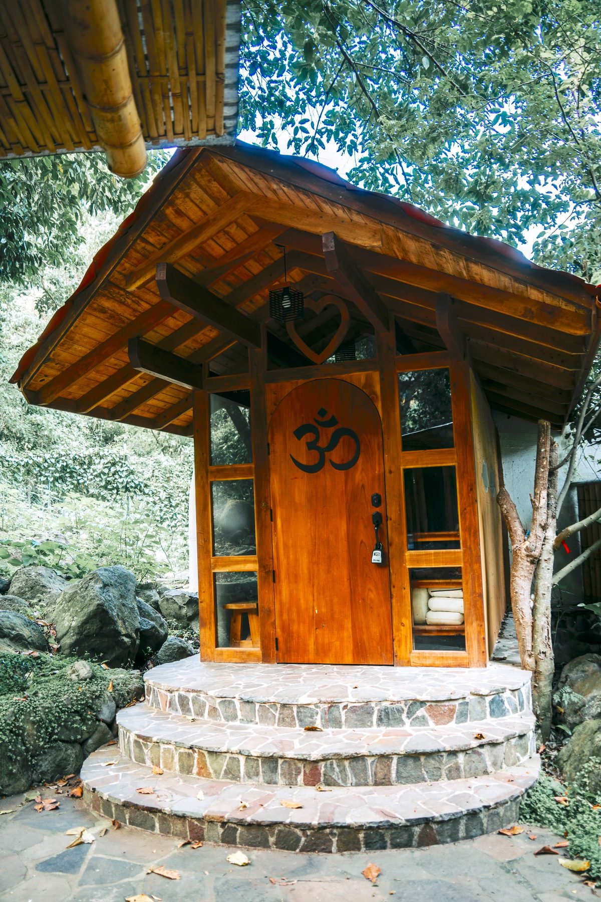 Wooden retreat cabin door with Om symbol among jungle foliage
